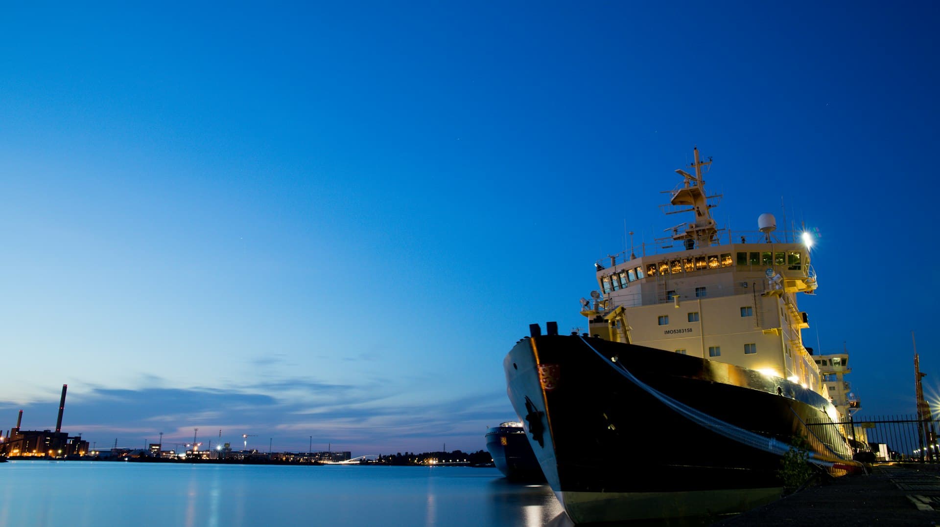 Navio atracado ao anoitecer sob vigilância